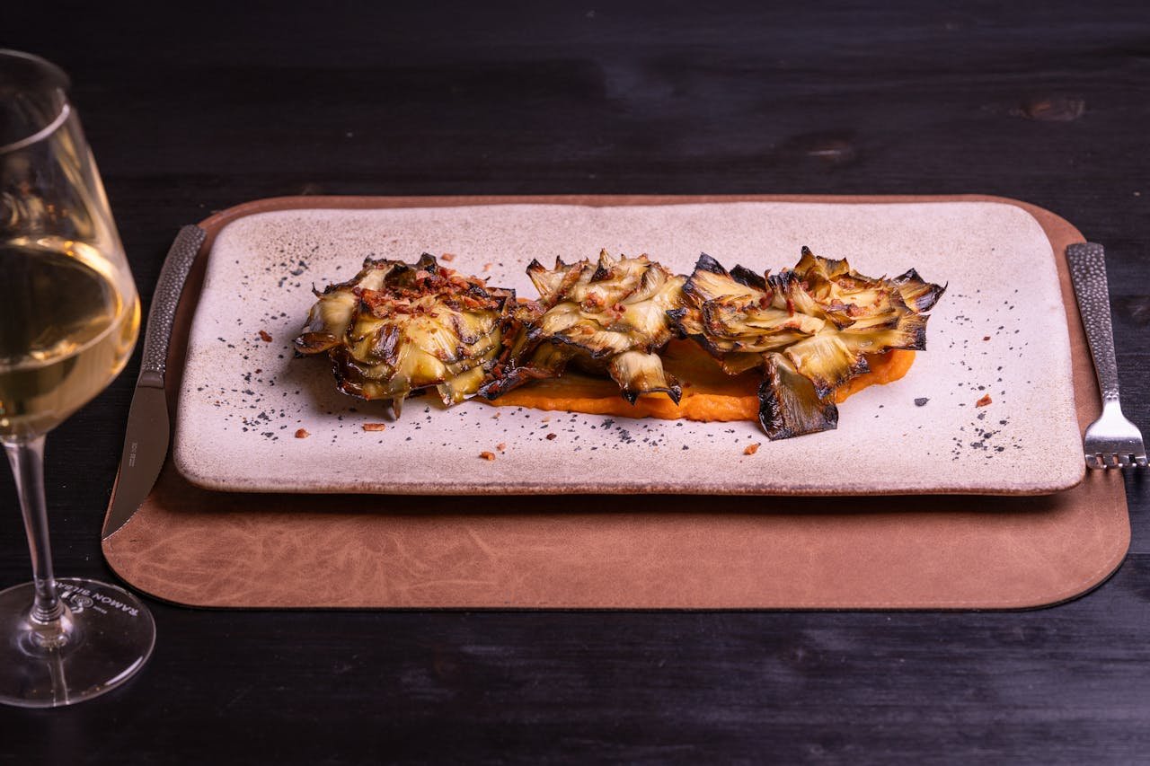 Deliciously grilled artichokes served on a modern plate with wine, perfect for culinary presentations.